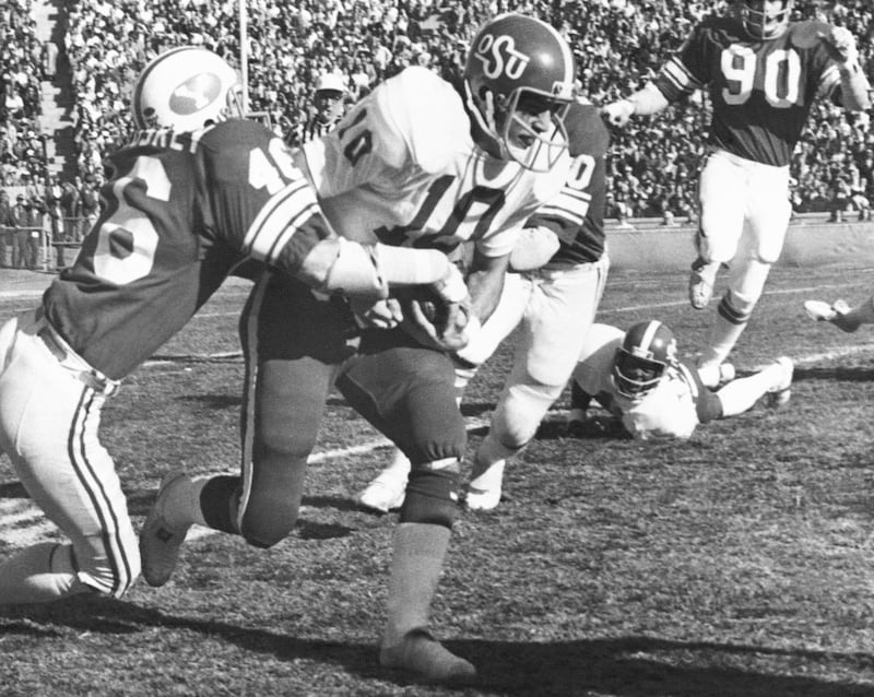 Oklahoma State quarterback Scott Burk, center, battles his way up the middle in the Fiesta Bowl, Saturday, Dec. 28, 1974, Tempe, Ariz. Attempting to make the tackle is BYU linebacker Mark McCluskey. Oklahoma State won the game, 16-6.