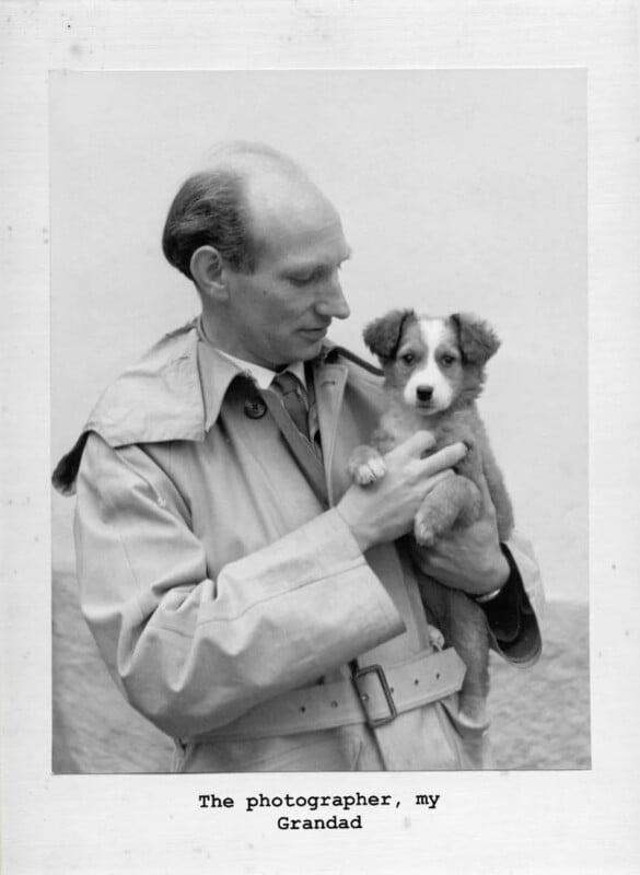 A black-and-white photo of an older man in a trench coat holding a small, fluffy puppy. He looks at the dog fondly. Typed text below the image reads, "The photographer, my Grandad.