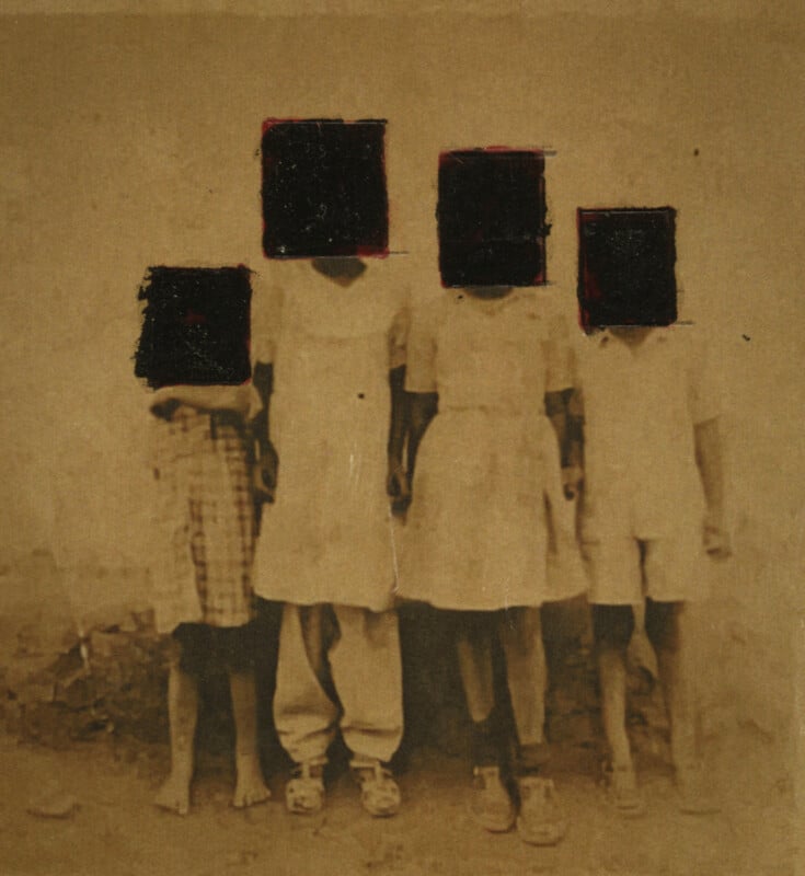 Four children stand side by side in an old, sepia-toned photograph; their faces are obscured by black squares, making them unidentifiable. The background is plain and worn.