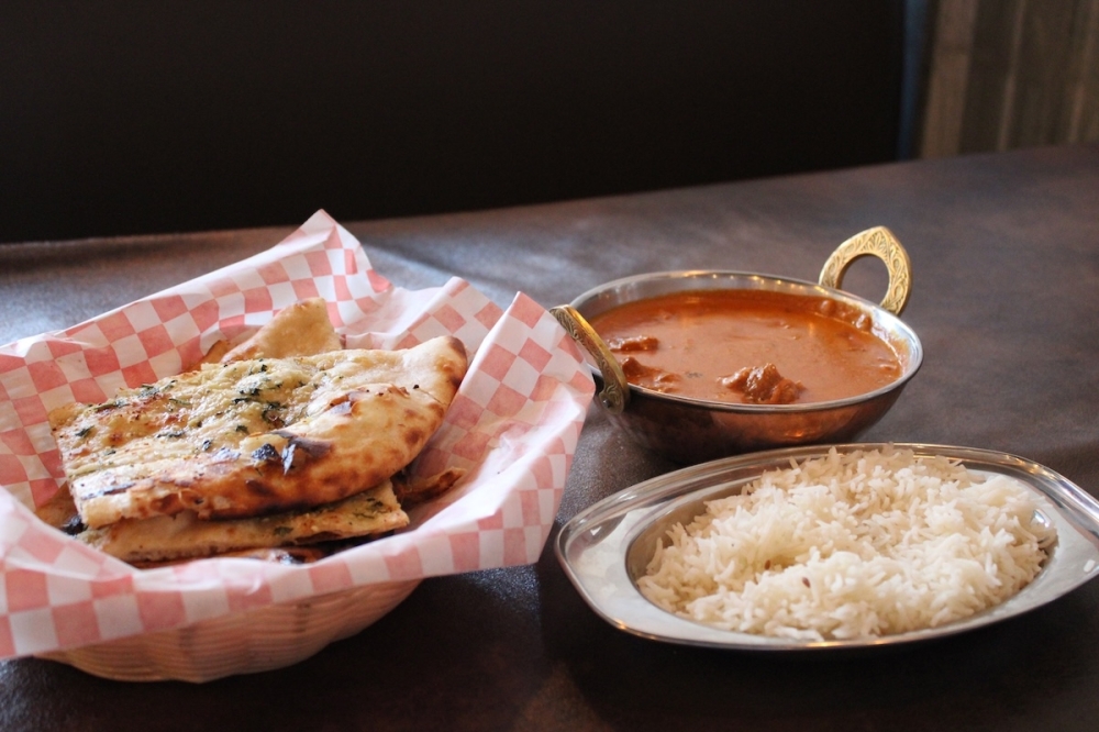 A classic lamb tikka masala dish is seen on a wooden table at a restaurant in Schertz, Texas.