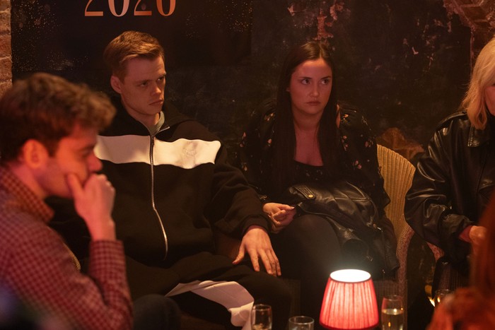 Peter, Lauren and Oscar look disgruntled sat in front of a 2026 banner in Harry's Barn in a scene from EastEnders