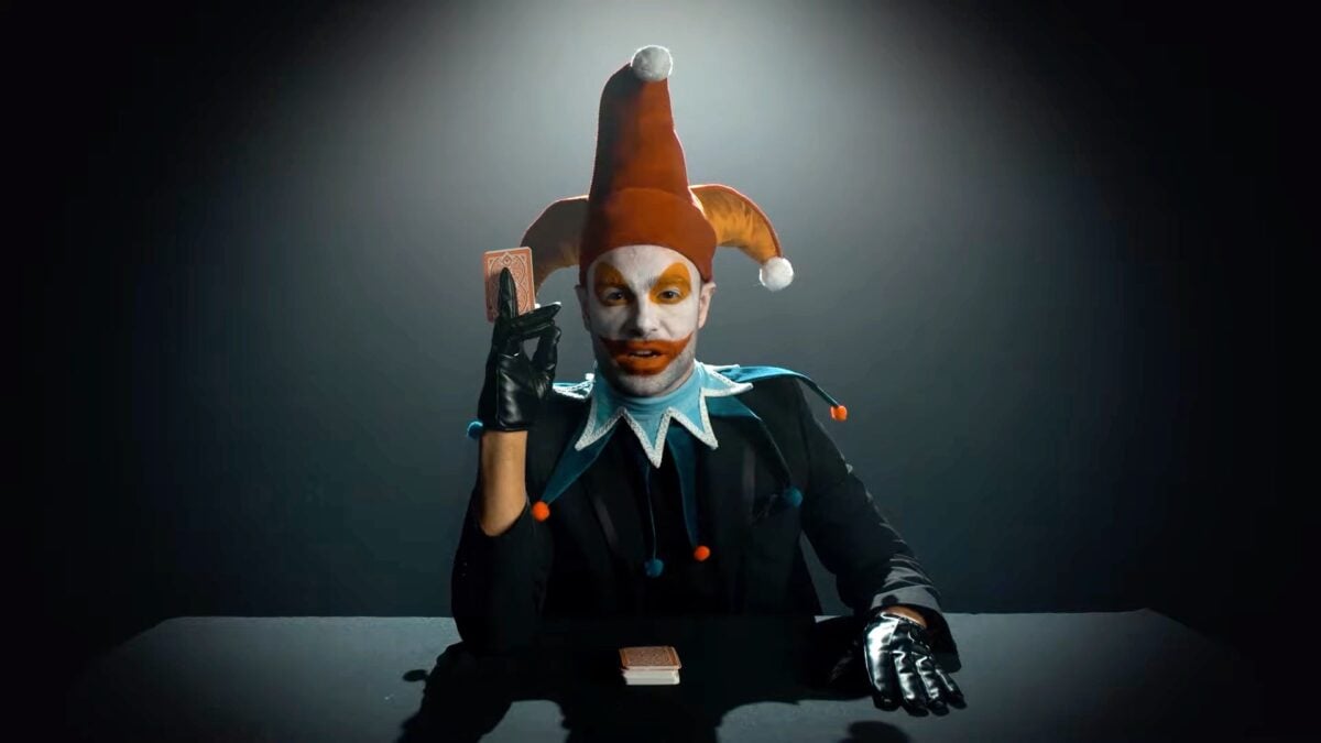 A man in a clown outfit plays with cards.
