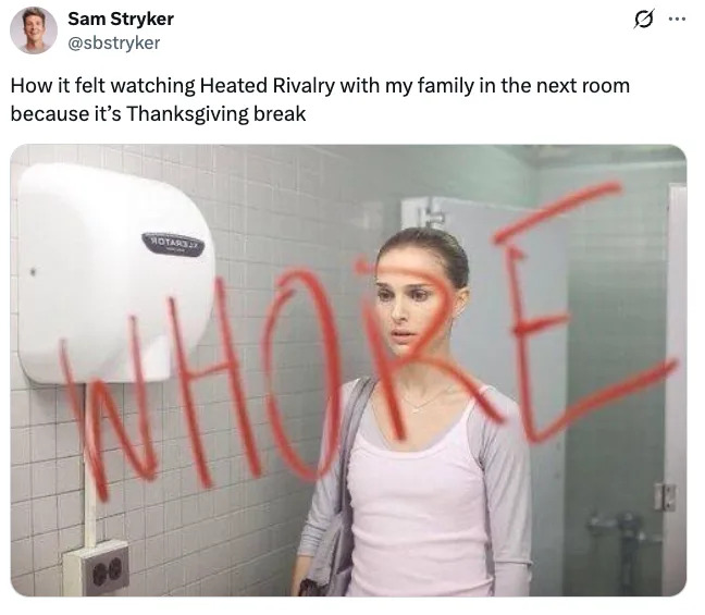 A person stands in a bathroom looking at a mirror with "WHORE" written on it in red