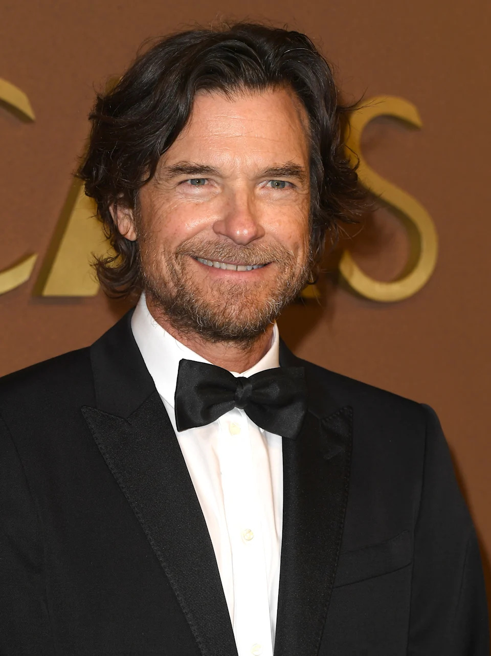 A man in a tuxedo with a bow tie smiling at an event