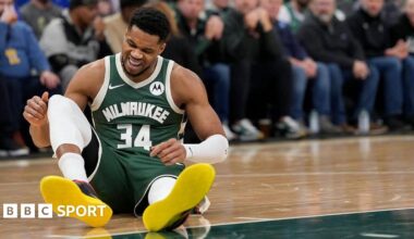 Giannis Antetokounmpo sits on the floor of the court with a pained expression on his face after picking up an injury