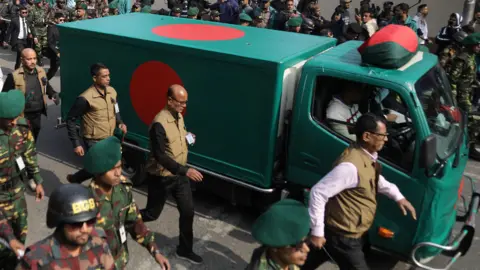 Reuters Security forces escort a flag-draped vehicle carrying the body of Khaleda in a motorcade. 