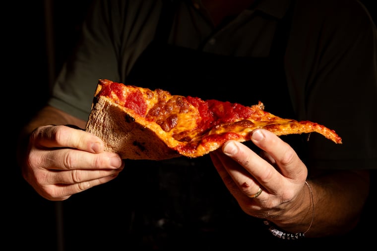Owner Steve Calozzi holds a slice of a 24 inch tomato pie at Italian Family Pizza on Monday, July 21, 2025, in Philadelphia.