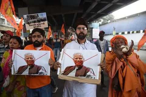 NurPhoto via Getty Images n Kolkata, India, on December 22, 2025, members of the Bharatiya Janata Party (BJP) and religious activists burn posters of Muhammad Yunus, Chief Adviser of Bangladesh's interim government, during a protest near the Deputy High Commission of Bangladesh in Kolkata. The demonstration follows reports of recent violence in Bangladesh after the killing of student leader Sharif Osman Hadi and the death of Hindu garment worker Dipu Chandra Das on December 18 amid allegations of blasphemy. (Photo by Debajyoti Chakraborty/NurPhoto via Getty Images)