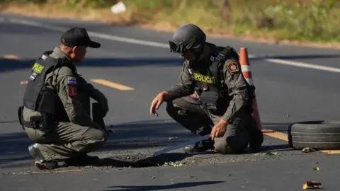 AP Two soldiers inspect a whole in a road left by a bomb. 