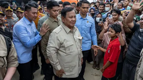 Getty Images Indonesia President Prabowo Subianto (centre, wearing cream shirt) is surrounded by a crowd of residents during his visit to Aceh Tamiang following the deadly floods