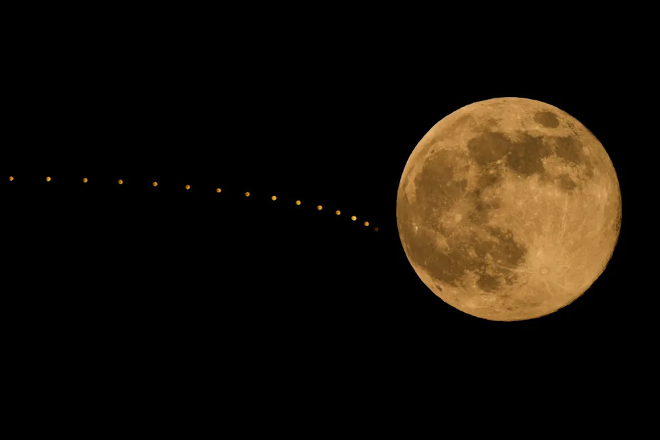 The supermoon rises beyond lights atop a hotel in Kansas City, Mo.
