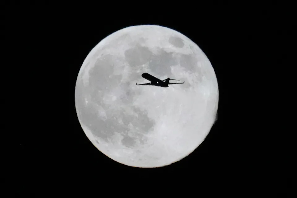 The silhouette of a plane as the supermoon rises on Dec. 4.