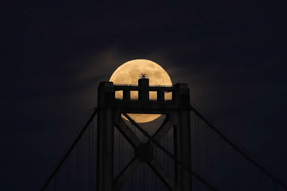 The silhouette of a bridge can be seen against the brightness of the last full moon of the year.