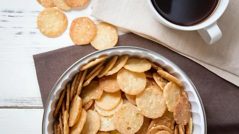Benne wafers in a tin, beside it some loose wafers and a cup of coffee