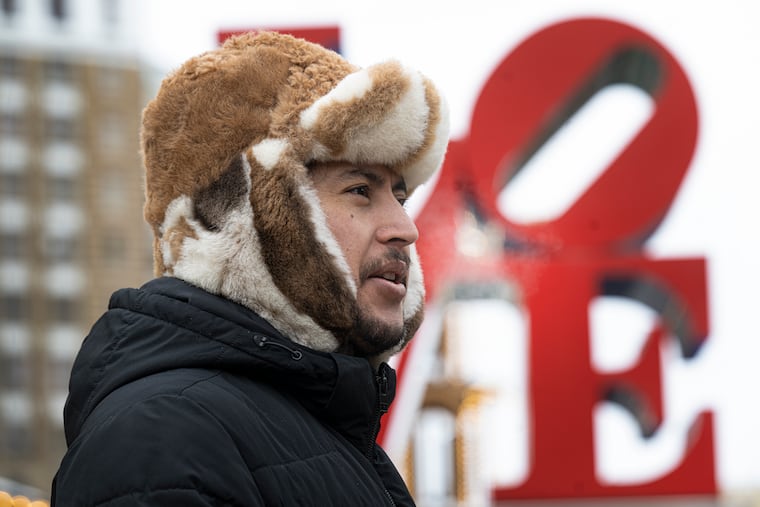 Nassim Hassanzada keeps his head warm against the cold wind at LOVE Park in Philadelphia on Monday. After what will be a very brief warmup, temperatures will crash Friday with wind gusts to 50 mph.