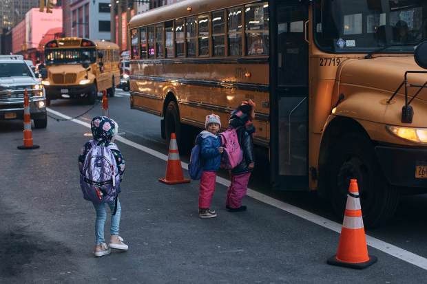 Migrant kids take a school bus in front of the Row Hotel that serves as migrant shelter on Tuesday, Dec. 12, 2023, in New York. (AP Photo/Andres Kudacki)