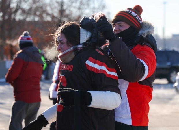 John Toomey of Arlington Heights helps his girlfriend, Julia O'Leary, put on her Browns jersey over her coat while tailgating before a Bears-Browns game Sunday, Dec. 14, 2025, at Soldier Field. (Dominic Di Palermo/Chicago Tribune)