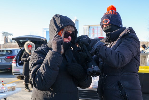 Jodie Reyes of Wauconda, right, helps her friend Nicole Shrum of Johnsonburg with her hood while tailgating before a Bears-Browns game Sunday, Dec. 14, 2025, at Soldier Field. (Dominic Di Palermo/Chicago Tribune)