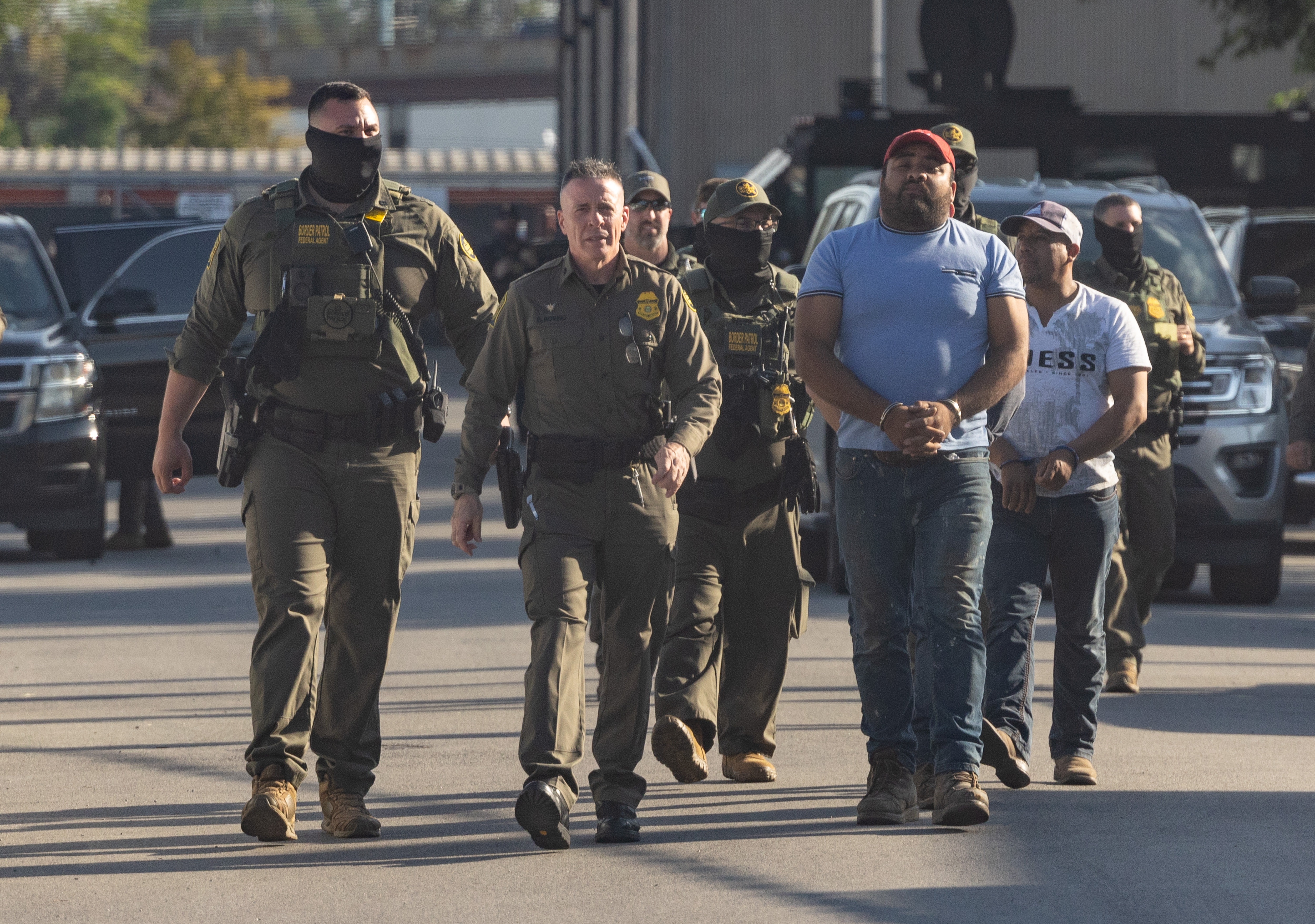 U.S. Border Patrol Chief Greg Bovino leads detainees into the...