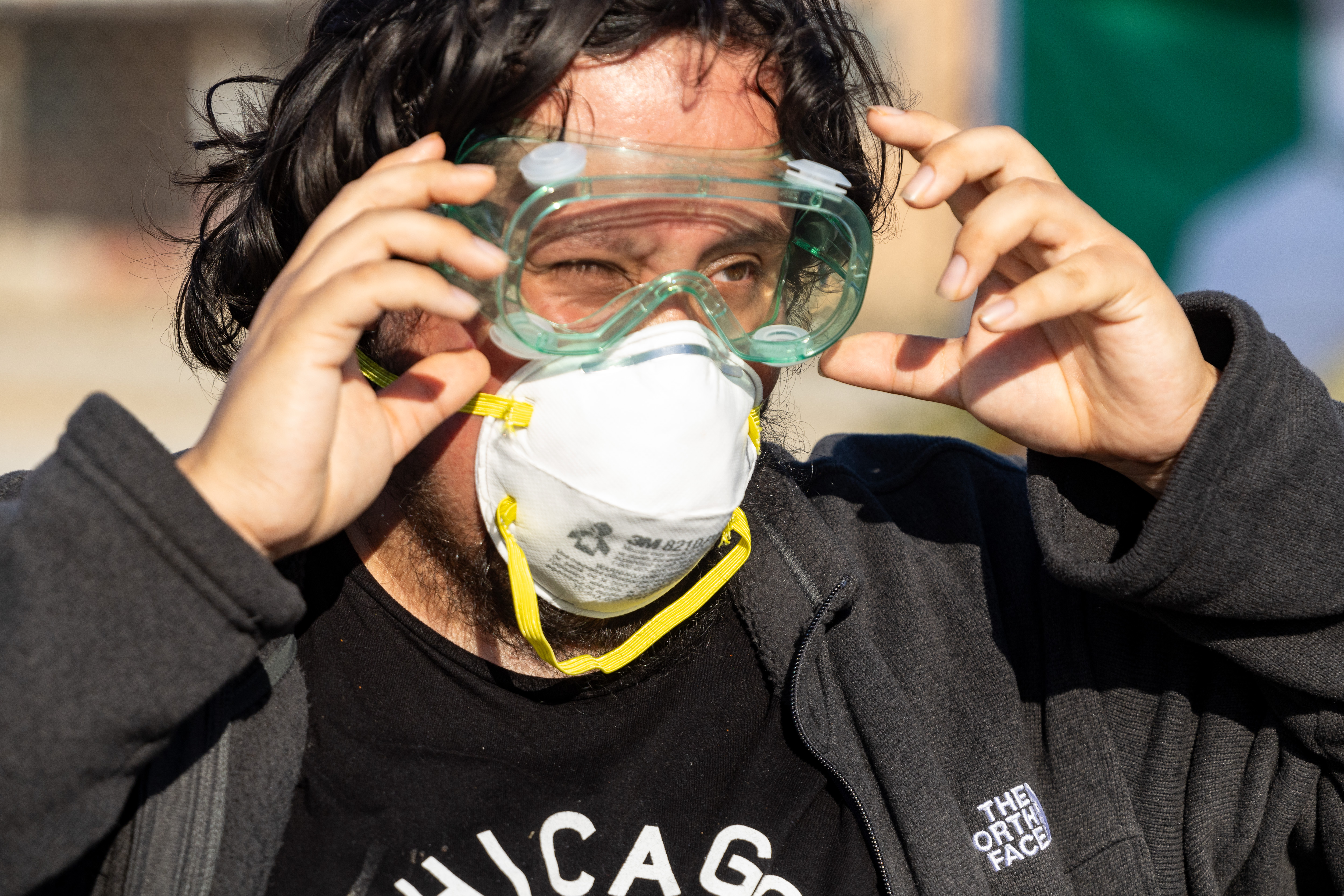 A protester wipes his eyes after being sprayed by a...
