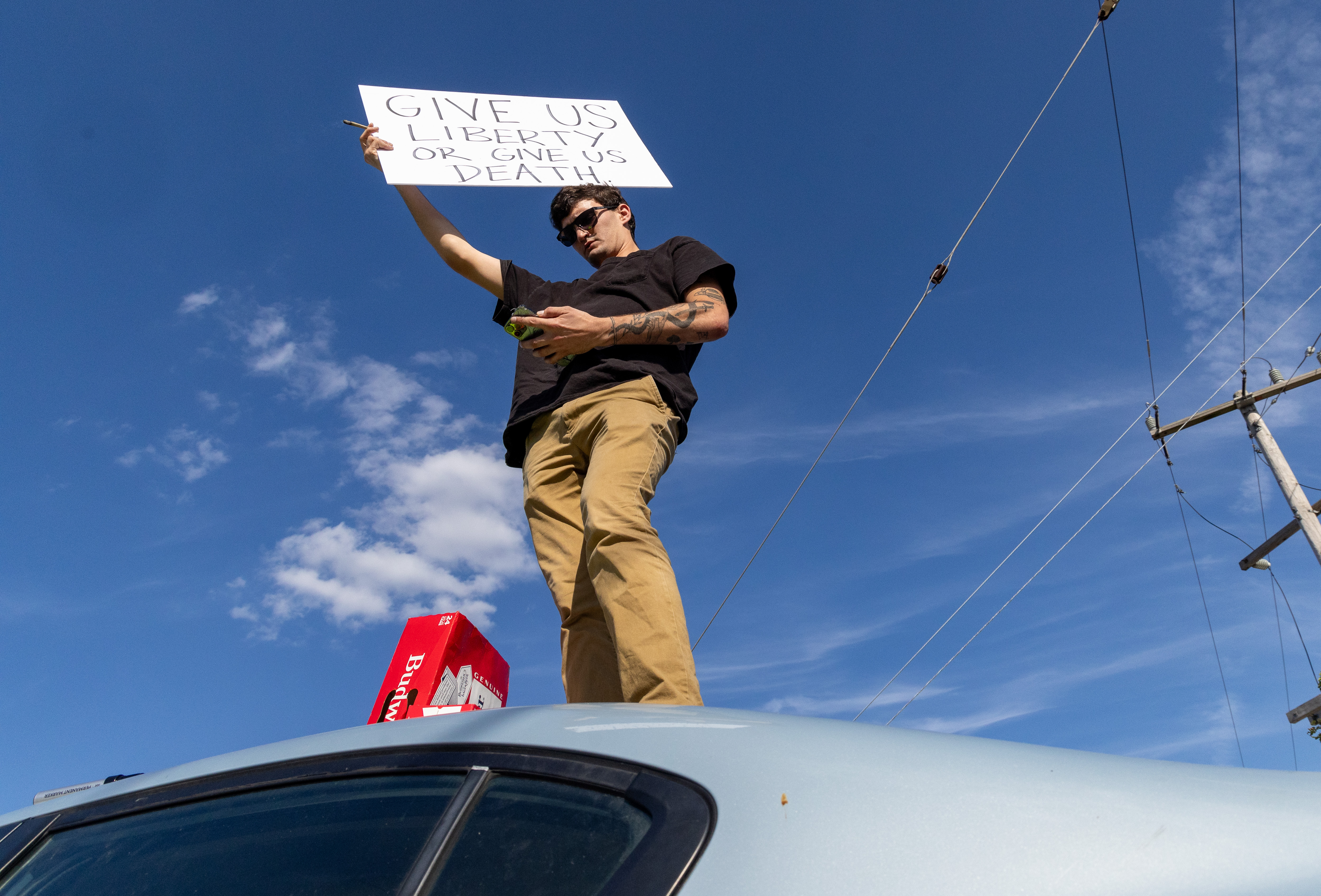 Logan Woodrum, of Pontiac, protests from the top of his...