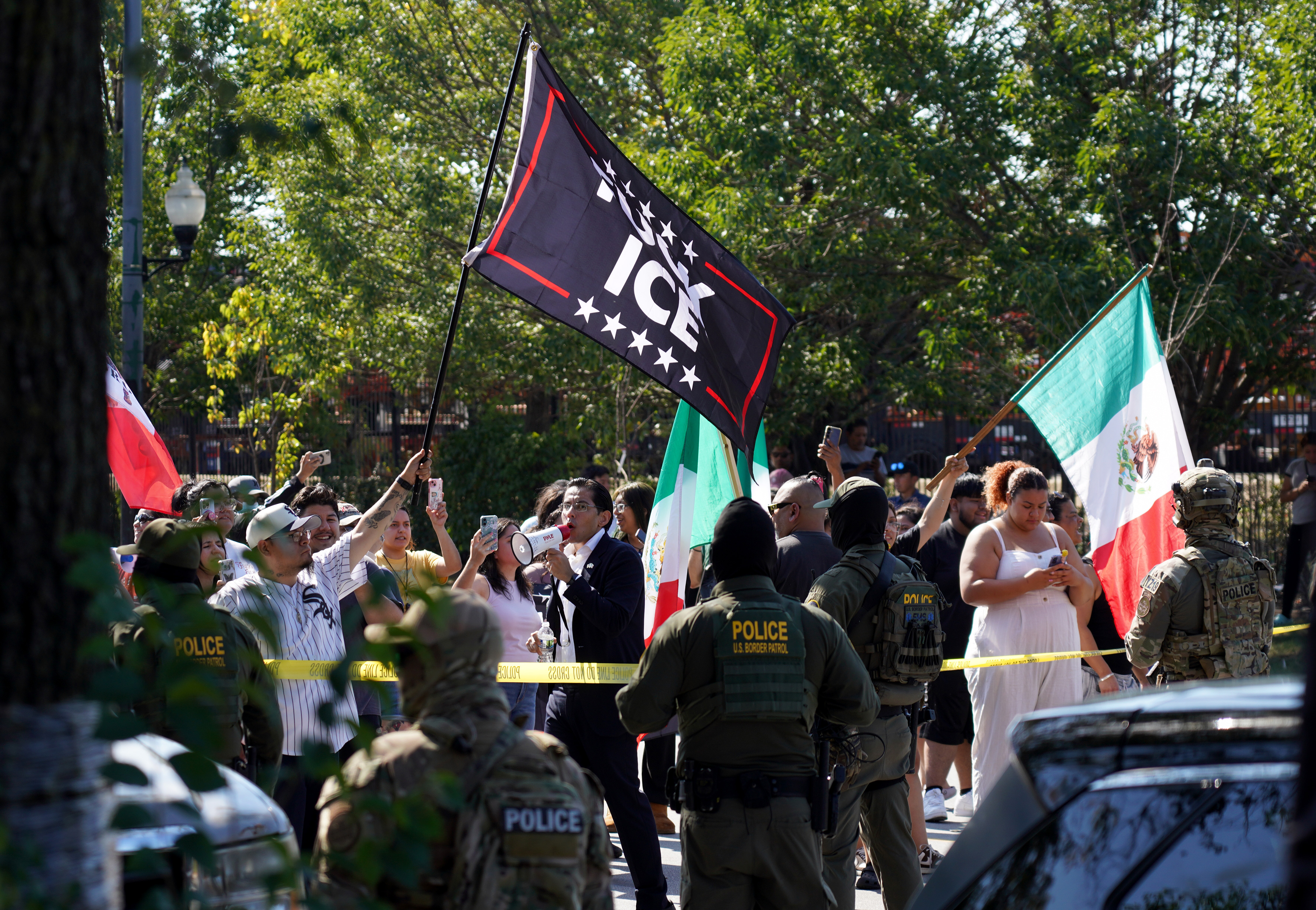 People protest as federal immigration agents conduct an investigation in...