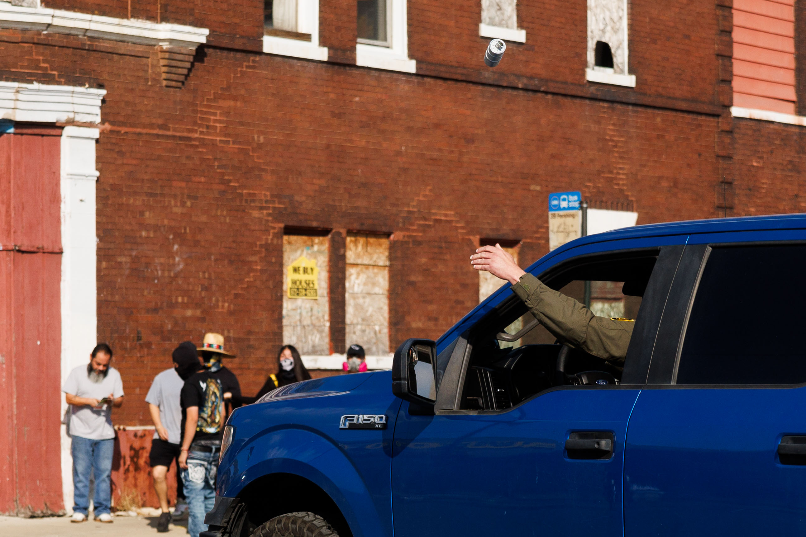 A federal agent lobs a gas canister at protesters near...