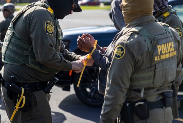 U.S. Border Patrol agents exchange handcuffs for plastic zip-ties while transferring detainees in Niles on Oct. 31, 2025. The detainees were picked up while they were landscaping on Chicago's Northwest Side. (Brian Cassella/Chicago Tribune)
