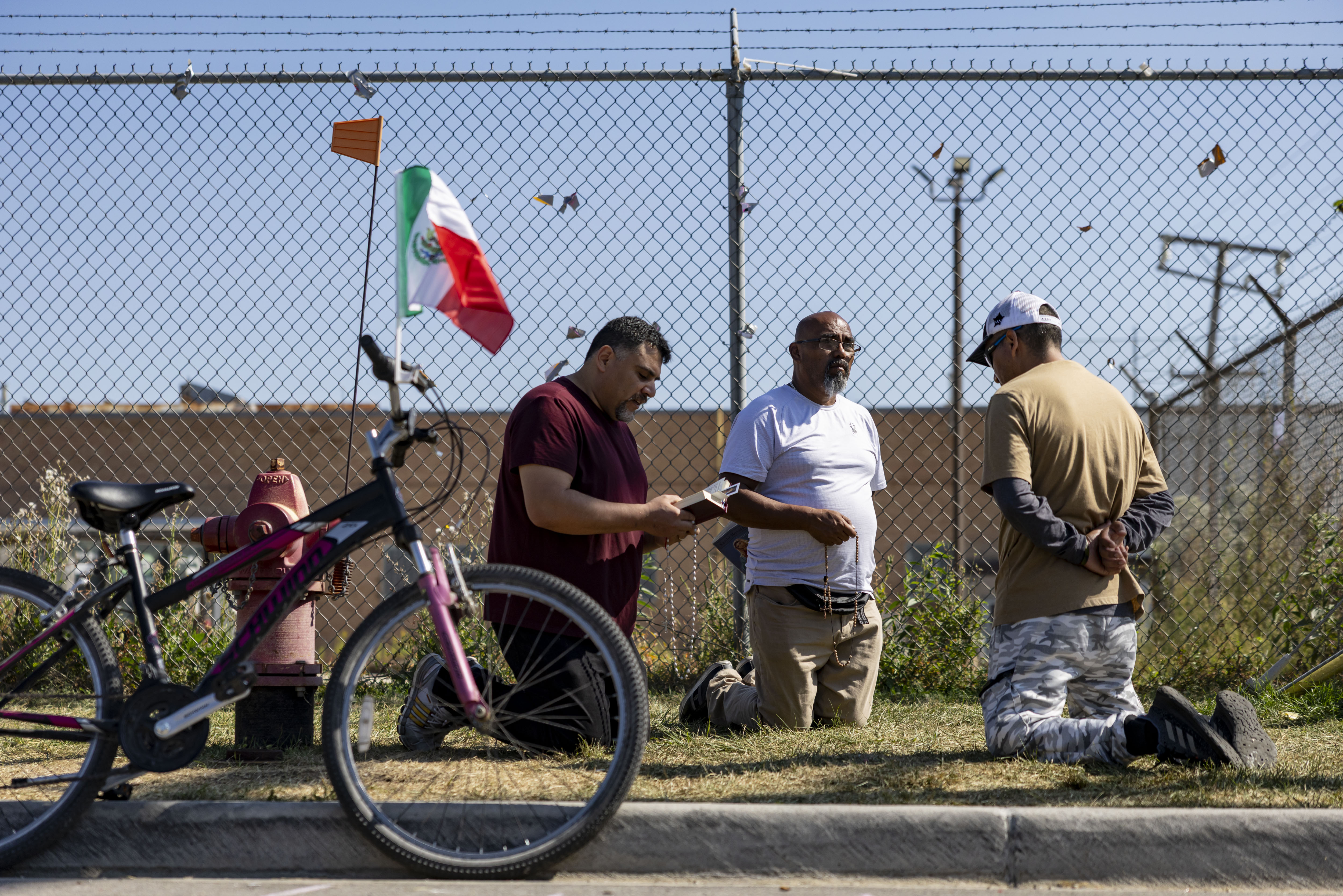 People pray on Sept. 28, 2025, near the U.S. Immigration...
