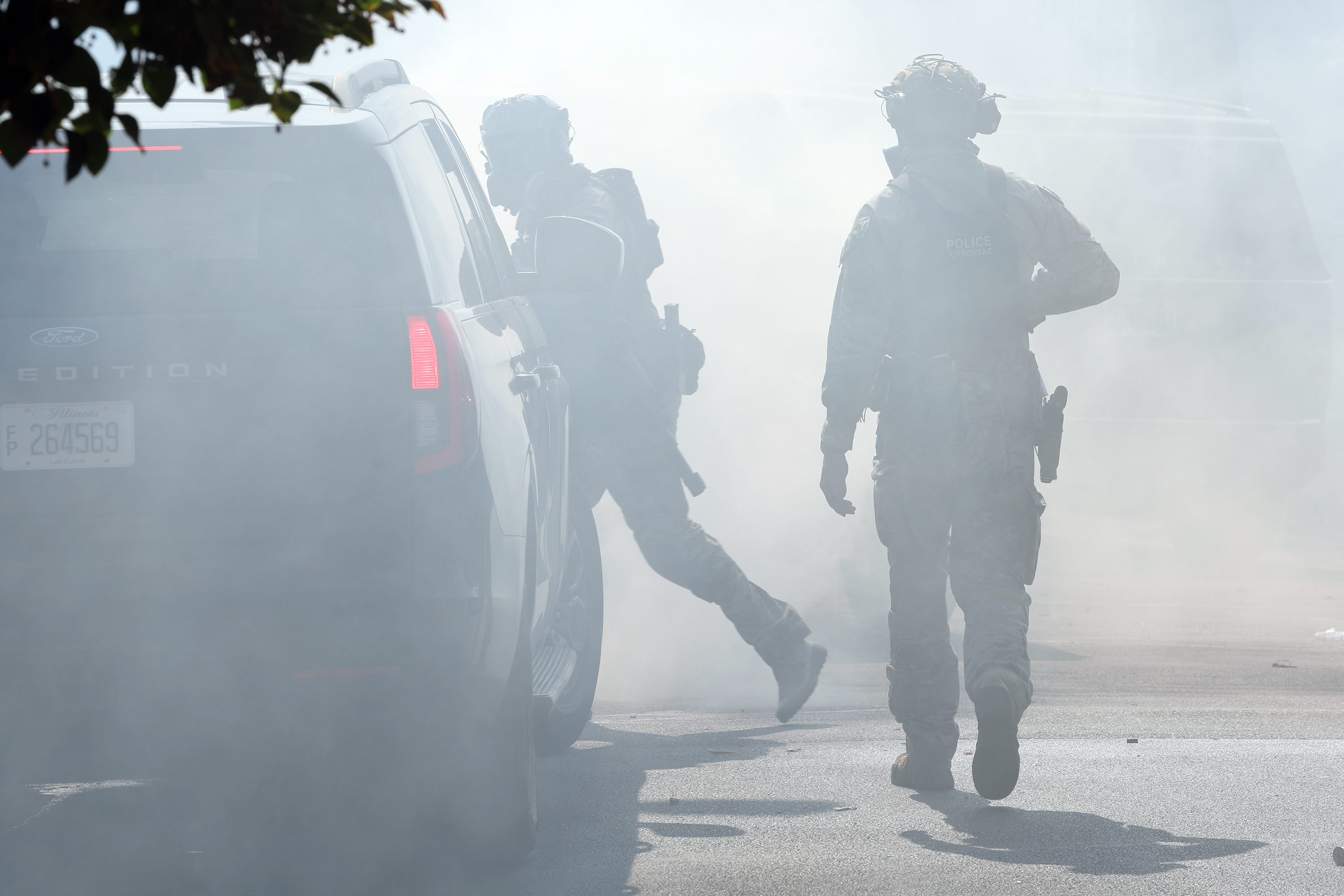 Border Patrol agents walk through a cloud of tear gas...