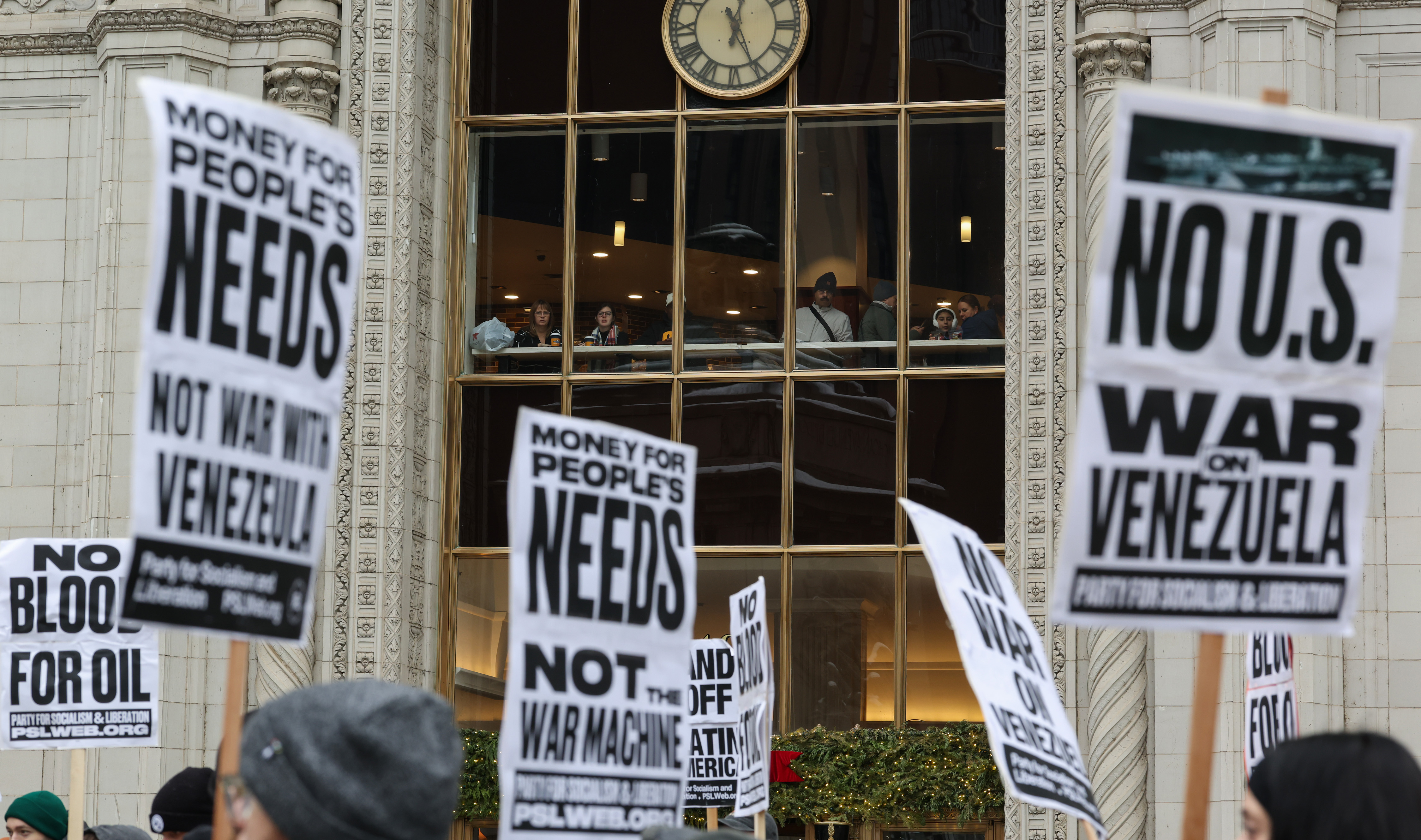 People in a second-floor cafe watch as demonstrators call attention...
