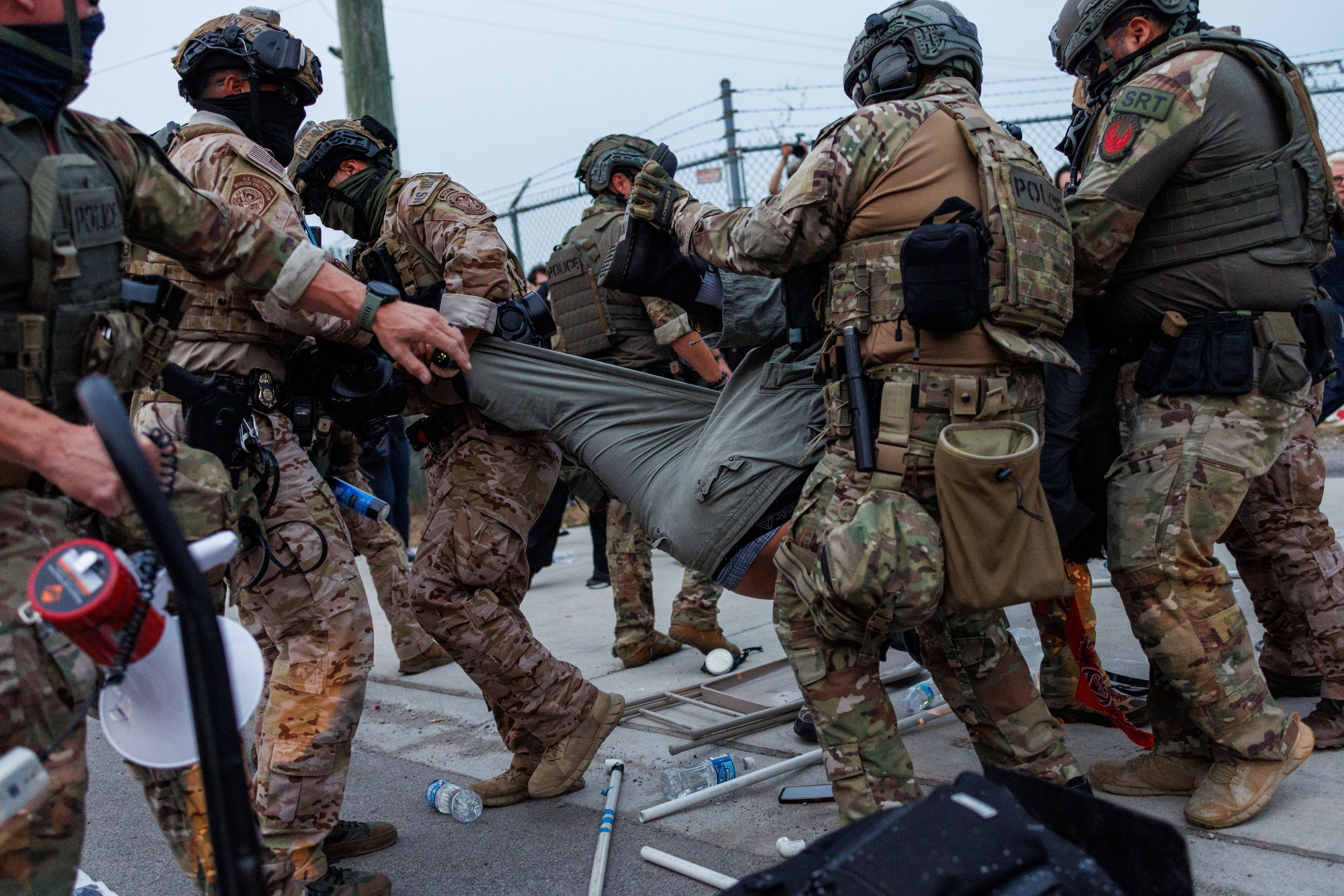 Federal law enforcement officers detain a protester outside the Immigration...