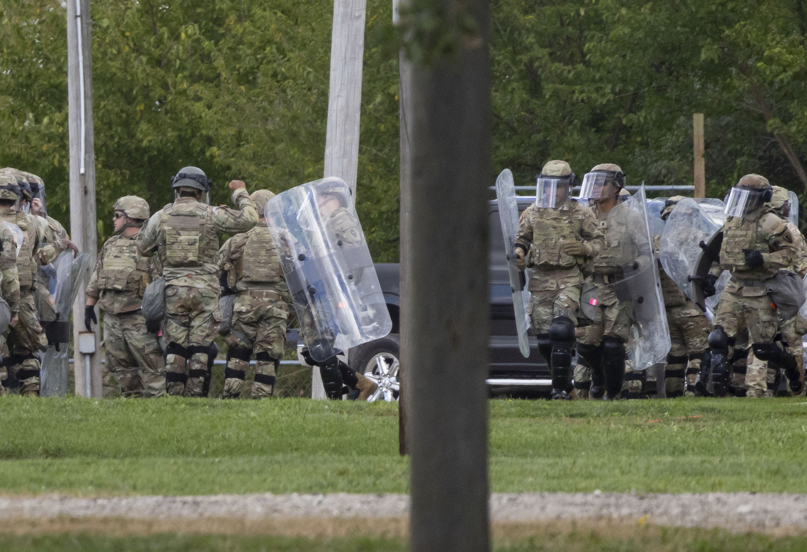 Members of the Texas National Guard carry shields while running...