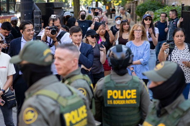 People watch as federal agents march near the Newberry Library in Chicago's Gold Coast on Sept. 28, 2025, after walking through downtown as part of an immigration blitz show of force. (Brian Cassella/Chicago Tribune)