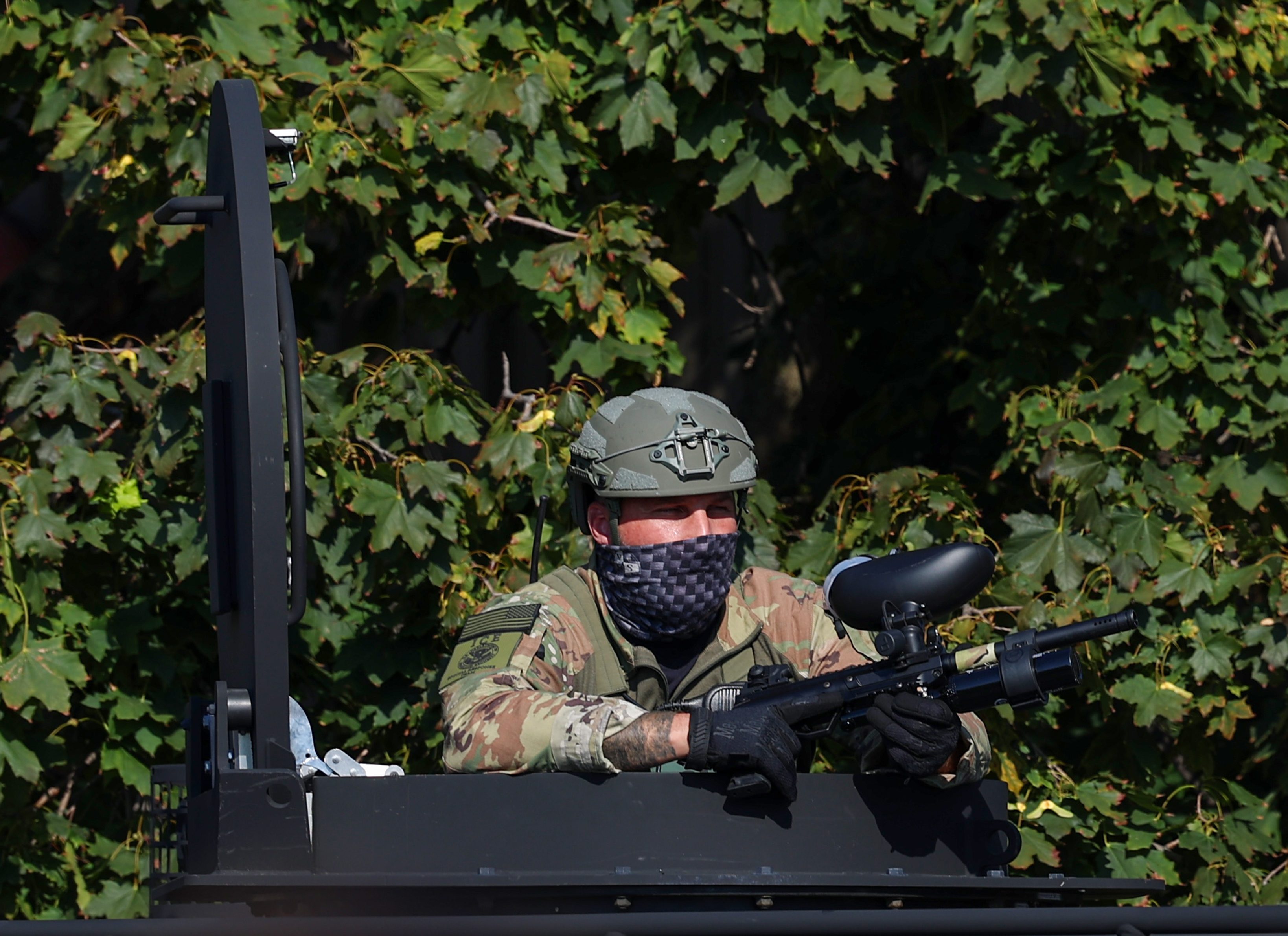 A federal agent watches from an armored vehicle near the...