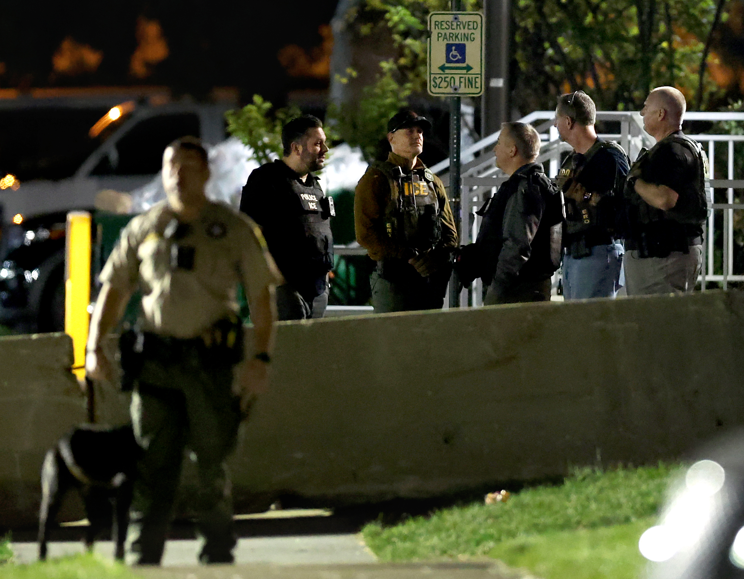 Immigration and Customs Enforcement officers stand near concrete barriers where...