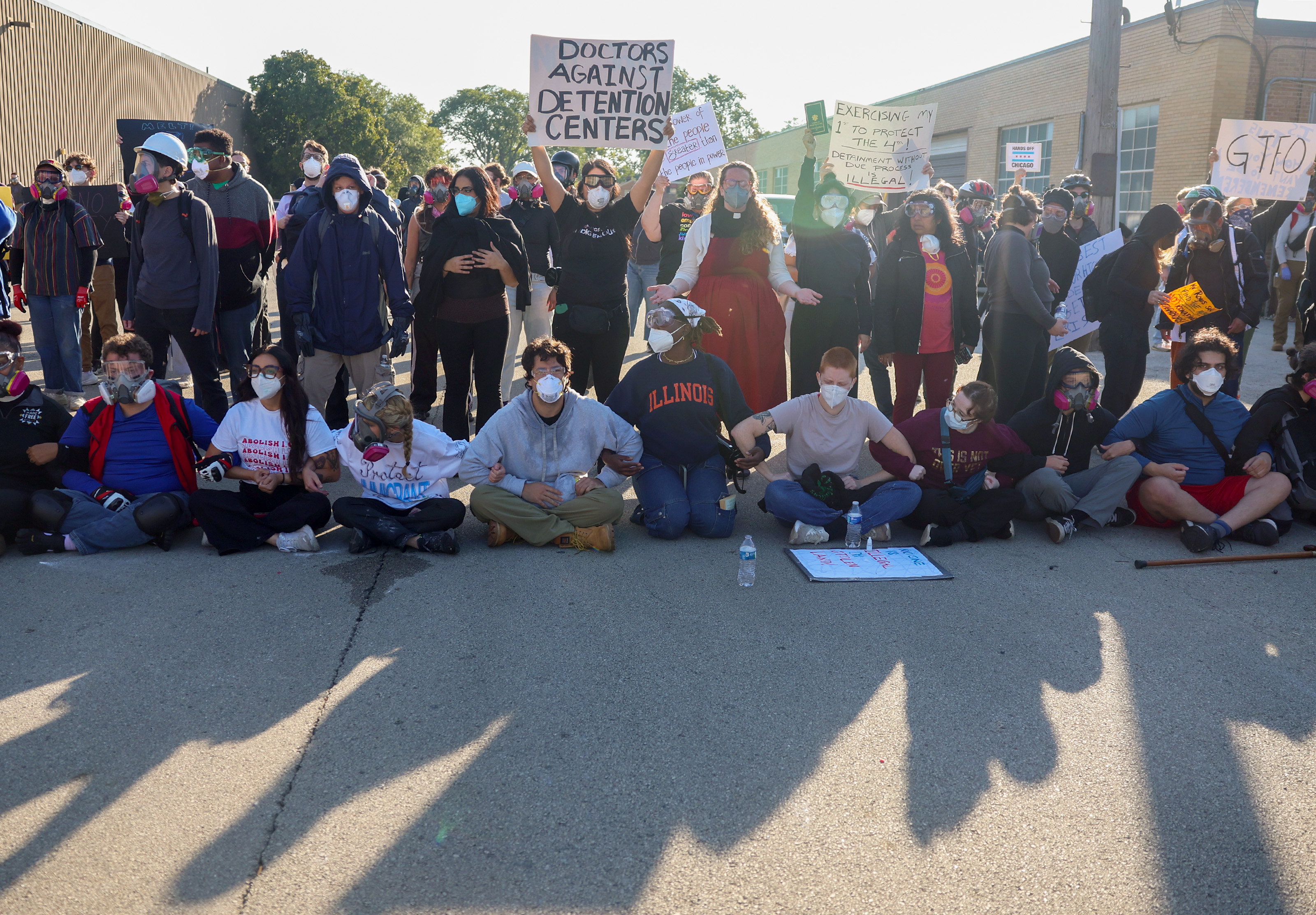 Protesters lock arms and block Harvard Street while federal agents...