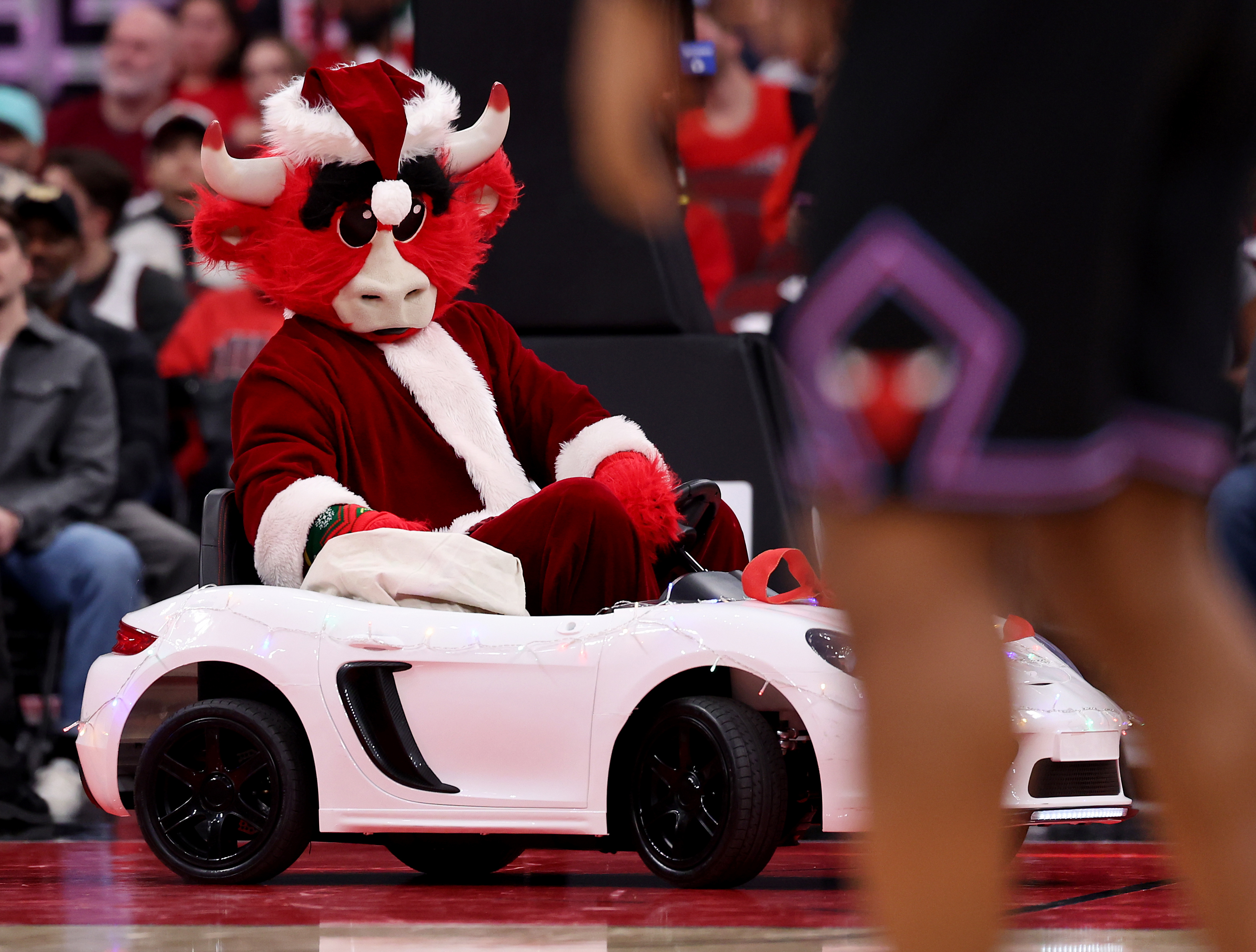 Benny the Bull, dressed as Santa Claus, drives a small...