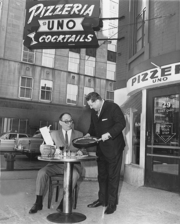 Lou Malnati, right, serves his father Rudy Malnati, proprietor of Pizzeria Uno, the 2 millionth pizza his two restaurants have turned out in 23 years of business on June 10, 1966, in Chicago. (Luigi Mendicino/Chicago Tribune)