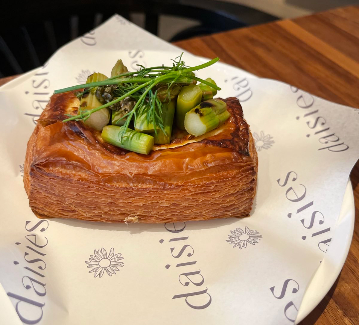 An asparagus Danish on a plate lined with Daisies paper.