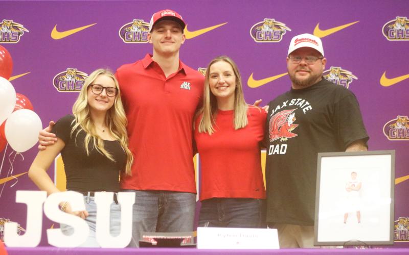 Columbia defensive end Kyten Davis (middle left) stands on stage alongside his family during his signing ceremony to attend Jacksonville State on Friday. (JORDAN KROEGER/Lake City Reporter)