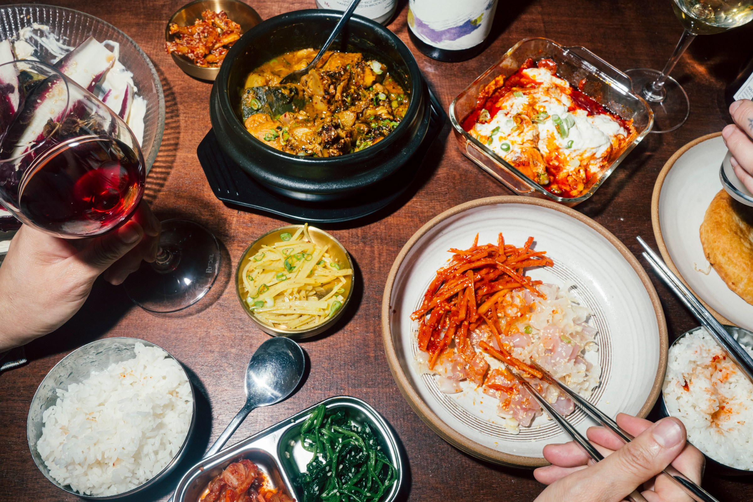 An assortment of banchan in stone bowls, ceramic plates, and metal bowls.