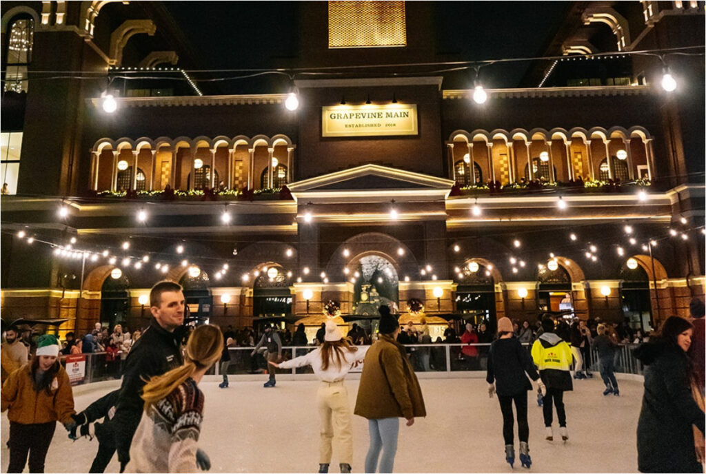 Image shows a group of people ice skating at Peace Plaza in front of Grapevine Main Station.