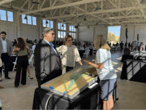A man and a woman stand in front of a watershed model display.