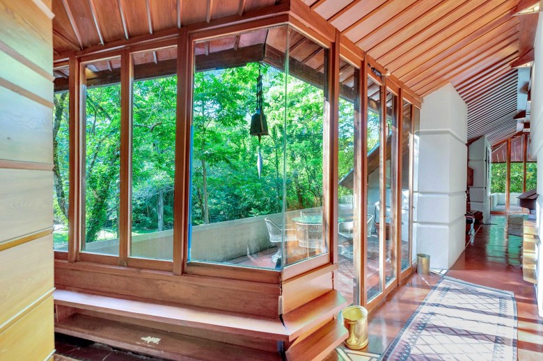 A view of the back porch of the Fountainhead hoe as seen through an interior rooms walls of glass