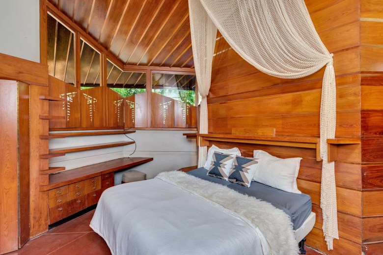 A bedroom in the fountainhead, structural surfaces all made of wood with built in shelving and window coverings
