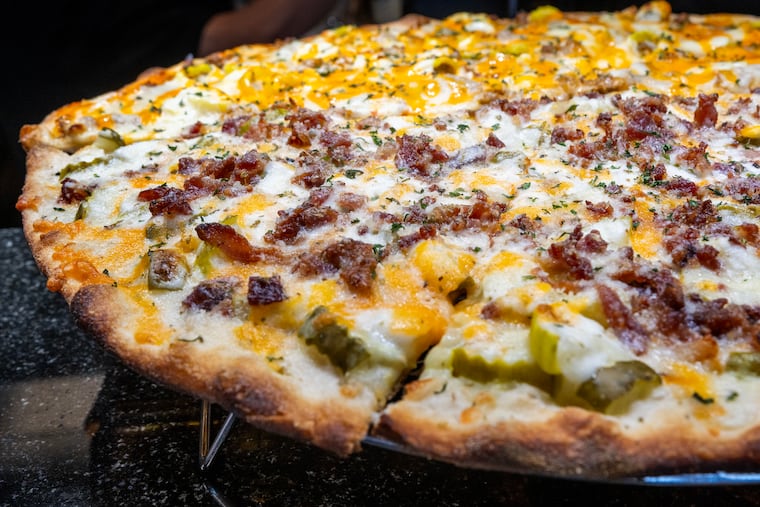 Half of a Pickle Pizza  (front: pickles, bacon, cheddar, mozzarella and ranch dressing) and half Zinger Pizza  (rear: secret sauce, steak, banana peppers, mozzarella and American cheese) at Gary Lincoln’s newly opened Knot Like the Rest Pizzeria in Pine Hill, N.J. Thursday, Oct. 16, 2025.