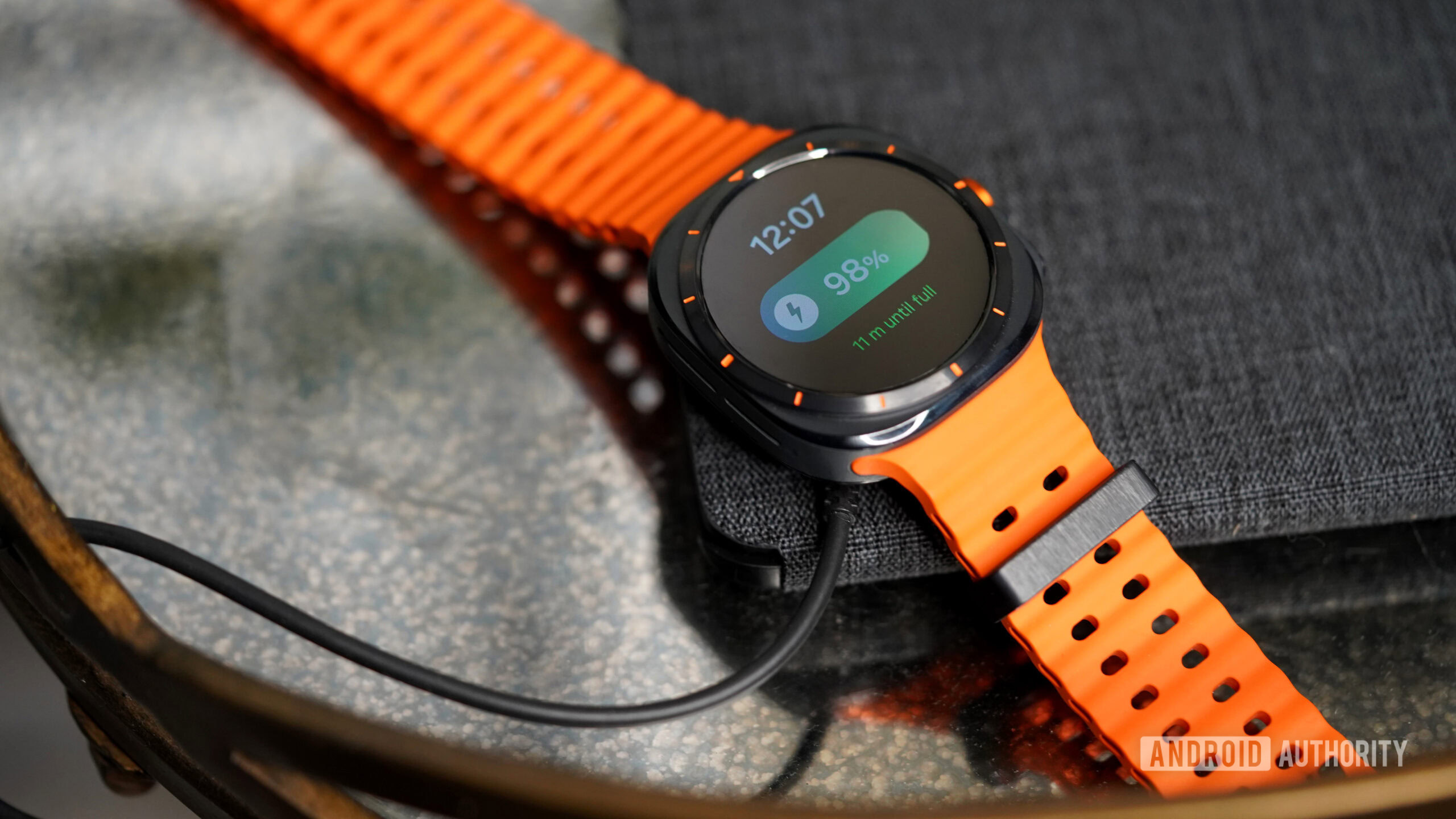 A Galaxy Watch Ultra rests on its charger.