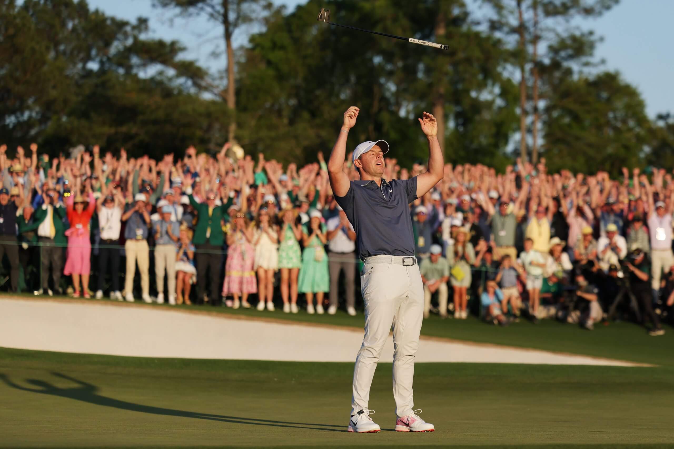Rory McIlroy tosses his putter into the air and throws both arms up as he rejoices in winning the 2025 Masters.