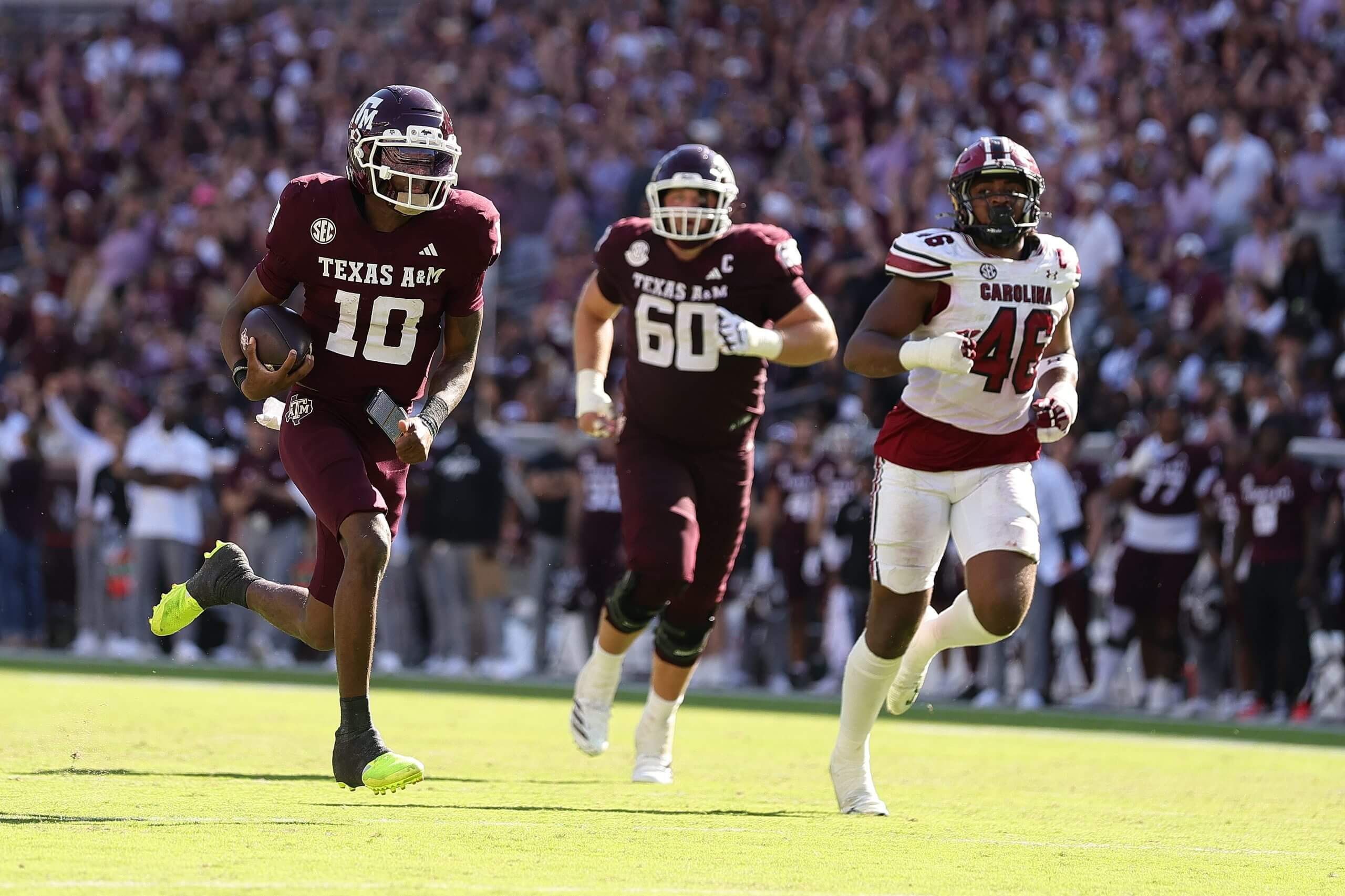 Texas A&M quarterback Marcel Reed runs with the football in his left arm as a South Carolina defender trails